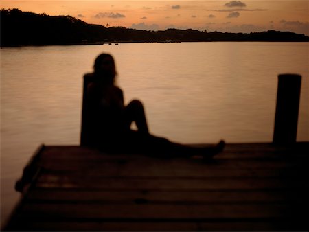 silhouette people sitting on a dock - Silhouette of a young woman sitting on pier Foto de stock - Sin royalties Premium, Código: 625-01093240