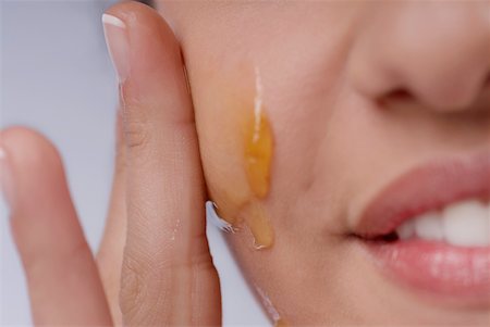 Close-up of a woman applying honey on her cheek Stock Photo - Premium Royalty-Free, Code: 625-01093421