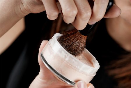 Close-up of a woman's hand holding a pot of face powder and a make-up brush Stock Photo - Premium Royalty-Free, Code: 625-01093475