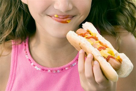 people eating hot dogs - Close-up of a girl eating a hot dog Stock Photo - Premium Royalty-Free, Code: 625-01093555