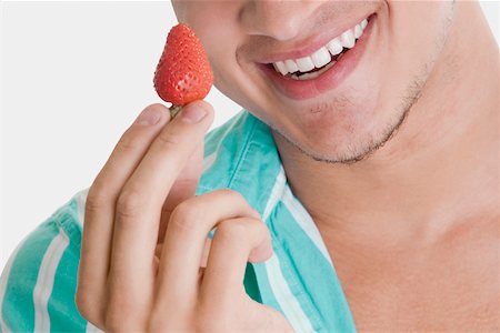 simsearch:625-00850090,k - Gros plan d'un jeune homme tenant une fraise et souriant Photographie de stock - Premium Libres de Droits, Code: 625-01093551