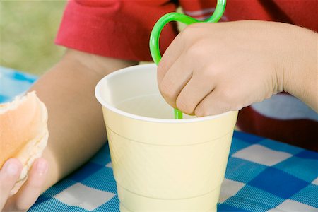 Mid section view of a child holding a burger and drinking with a straw Foto de stock - Sin royalties Premium, Código: 625-01093592