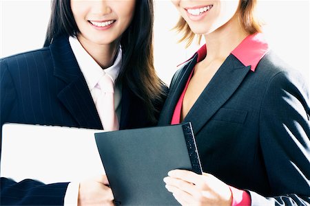 simsearch:625-00850993,k - Close-up of two businesswomen holding files and smiling Stock Photo - Premium Royalty-Free, Code: 625-01093608
