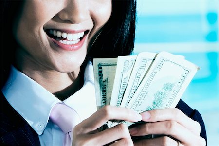 Close-up of a businesswoman counting dollar bills and smiling Stock Photo - Premium Royalty-Free, Code: 625-01093609
