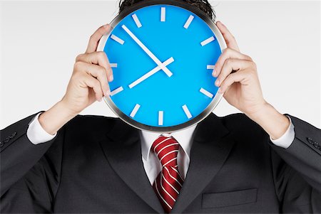 simsearch:625-01748576,k - Close-up of a businessman holding a clock in front of his face Foto de stock - Royalty Free Premium, Número: 625-01093713