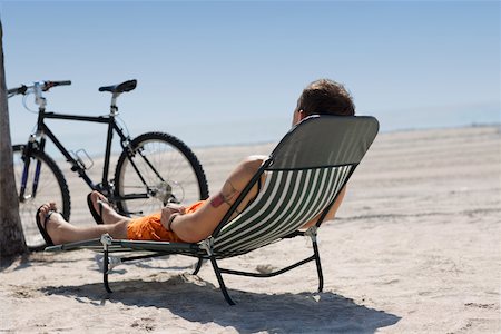 simsearch:625-01095436,k - Rear view of a man reclining on a lounge chair on the beach Stock Photo - Premium Royalty-Free, Code: 625-01093965