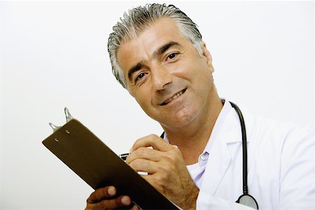 simsearch:625-02929220,k - Portrait of a male doctor writing on a clipboard and smiling Stock Photo - Premium Royalty-Free, Code: 625-01249692
