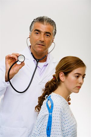 simsearch:625-01252198,k - Portrait of a male doctor standing beside a young woman and holding a stethoscope Foto de stock - Royalty Free Premium, Número: 625-01249787