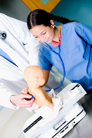 Girl examining a doll with a stethoscope and a male doctor standing beside her Stock Photo - Premium Royalty-Free, Code: 625-01249816