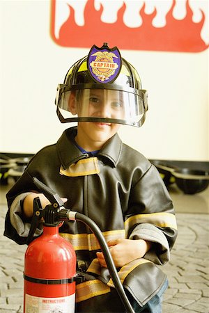 fireman and child - Close-up of a boy dressed as a firefighter and holding a fire extinguisher Stock Photo - Premium Royalty-Free, Code: 625-01249939
