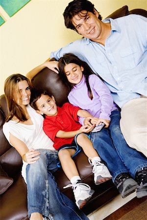 simsearch:6102-03905907,k - Mid adult couple with their children sitting on a couch and watching television Fotografie stock - Premium Royalty-Free, Codice: 625-01250294