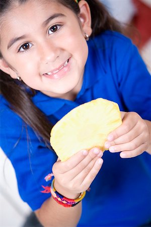 Portrait of a girl holding a slice of pineapple and smiling Stock Photo - Premium Royalty-Free, Code: 625-01250385