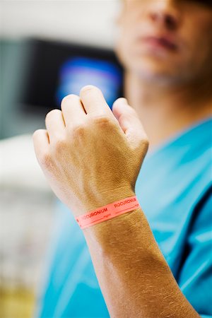 simsearch:625-02932810,k - Close-up of a mid adult man's hand with dosage tag around his wrist Fotografie stock - Premium Royalty-Free, Codice: 625-01250556