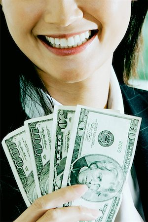 Close-up of a businesswoman holding American dollar bills and smiling Fotografie stock - Premium Royalty-Free, Codice: 625-01250847
