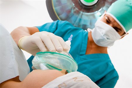 female in on oxygen mask for breathe - Male surgeon putting an oxygen mask on a female patient Stock Photo - Premium Royalty-Free, Code: 625-01250864