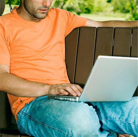 porch swing images - Gros plan d'un jeune homme à l'aide d'un ordinateur portable sur une balançoire de porche Photographie de stock - Premium Libres de Droits, Code: 625-01250878