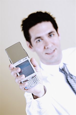 simsearch:625-02266709,k - Portrait of a businessman showing a mobile phone Foto de stock - Sin royalties Premium, Código: 625-01250982