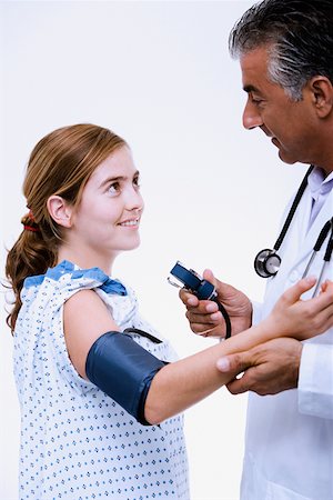 doctor patient standing white background - Side profile of a male doctor measuring blood pressure of a young woman Stock Photo - Premium Royalty-Free, Code: 625-01251085
