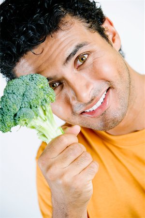 simsearch:625-01097164,k - Portrait d'un jeune homme tenant un brocoli et souriant Photographie de stock - Premium Libres de Droits, Code: 625-01251174