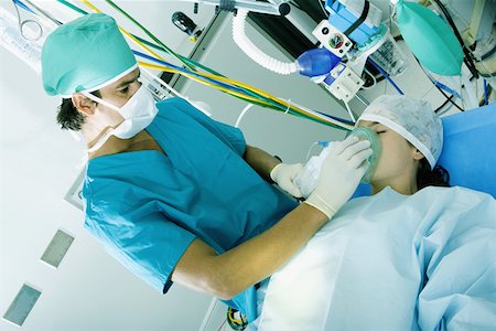 female in on oxygen mask for breathe - Male surgeon putting an oxygen mask on a female patient Stock Photo - Premium Royalty-Free, Code: 625-01251371