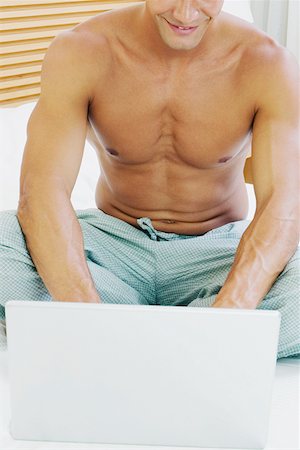 Close-up of a young man using a laptop on the bed Stock Photo - Premium Royalty-Free, Code: 625-01251653