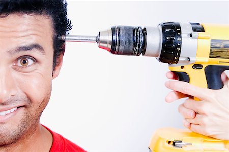 Close-up of a person's hands holding a drill machine at a young man's head Stock Photo - Premium Royalty-Free, Code: 625-01251913