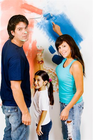 Portrait of a young man and a mid adult woman with their daughter painting a wall Stock Photo - Premium Royalty-Free, Code: 625-01251994
