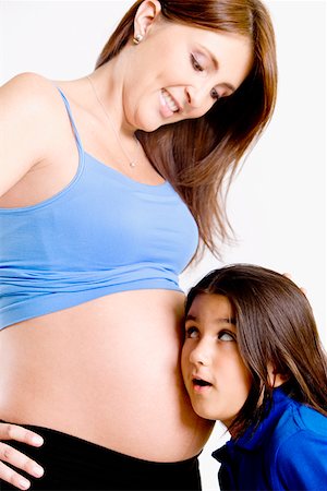 pregnant hispanic mom - Side profile of a girl listening to a pregnant young woman's abdomen Stock Photo - Premium Royalty-Free, Code: 625-01252291