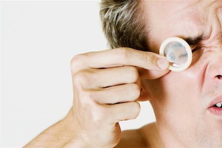 simsearch:625-01252359,k - Close-up of a young man holding a condom in front of his eye Stock Photo - Premium Royalty-Free, Code: 625-01252577