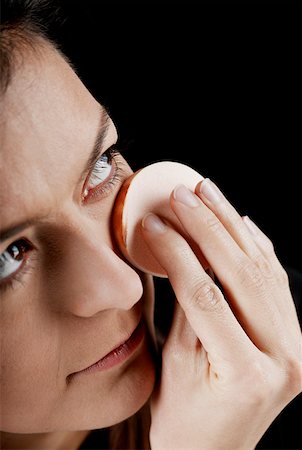 Close-up of a young woman applying face powder with a powder puff Stock Photo - Premium Royalty-Free, Code: 625-01264444