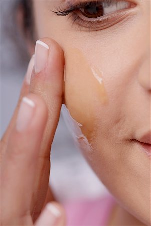 Close-up of a young woman applying honey on her cheek Stock Photo - Premium Royalty-Free, Code: 625-01264556