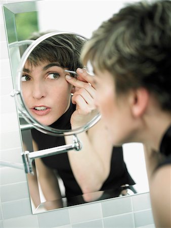 Reflection of a mature woman tweezing her eyebrows in a mirror Stock Photo - Premium Royalty-Free, Code: 625-01264560