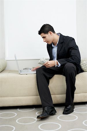 full body student holding laptop - Businessman holding US paper currency and using a laptop Stock Photo - Premium Royalty-Free, Code: 625-01264669