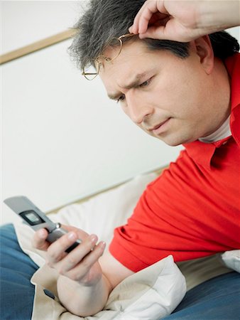 simsearch:625-01097695,k - Close-up of a mature man looking at a mobile phone and reclining on the bed Foto de stock - Royalty Free Premium, Número: 625-01264717