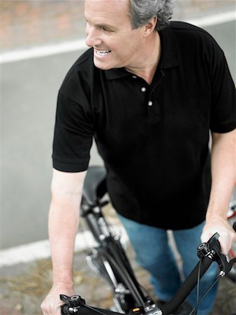 Vue grand angle sur un homme d'âge mûr permanent avec une bicyclette et souriant Photographie de stock - Premium Libres de Droits, Code: 625-01264877