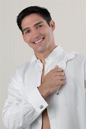 Portrait of a young man holding a bow tie on his shoulder Stock Photo - Premium Royalty-Free, Code: 625-01264929