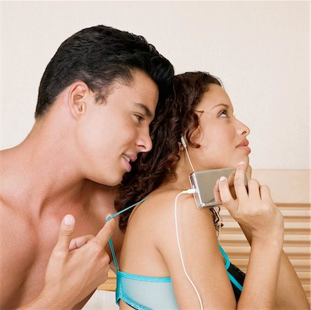 Teenage girl listening to an MP3 player with a young man sitting behind her Stock Photo - Premium Royalty-Free, Code: 625-01260666