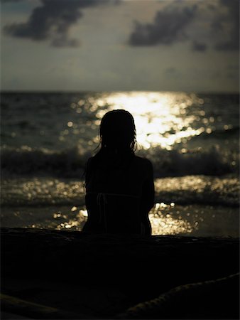 Rear view of a young woman sitting on the beach Stock Photo - Premium Royalty-Free, Code: 625-01260705