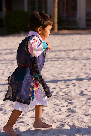 Side profile of a boy in traditional clothing walking on sand Stock Photo - Premium Royalty-Free, Code: 625-01261051