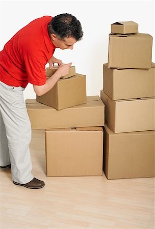 Side profile of a mid adult man packing cardboard boxes Stock Photo - Premium Royalty-Free, Code: 625-01261186