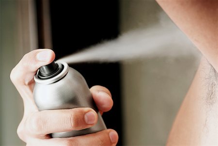 Mid section view of a young man spraying deodorant Stock Photo - Premium Royalty-Free, Code: 625-01261305