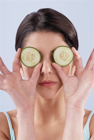 Close-up of a young woman covering her eyes with cucumber slices Stock Photo - Premium Royalty-Free, Code: 625-01261664
