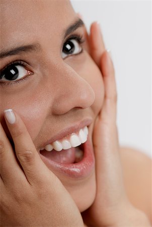 Close-up of a young woman laughing with her hands on her head Stock Photo - Premium Royalty-Free, Code: 625-01261892