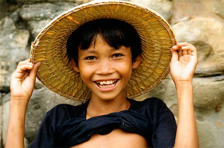 Portrait of a boy smiling and holding a straw hat, Angkor Thom, Angkor, Siem Reap, Cambodia Stock Photo - Premium Royalty-Free, Code: 625-01262237