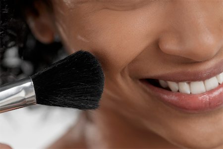 Close-up of a young woman applying blush with a brush Stock Photo - Premium Royalty-Free, Code: 625-01262603