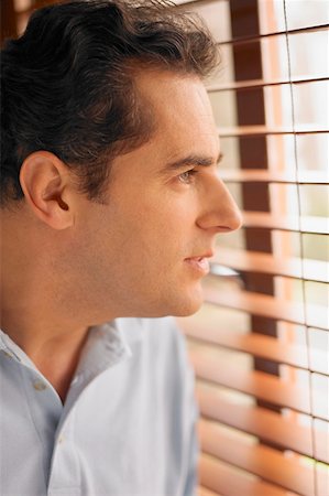 Close-up of a young man looking out of a window Stock Photo - Premium Royalty-Free, Code: 625-01262845