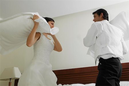 Newlywed couple having a pillow fight on the bed Stock Photo - Premium Royalty-Free, Code: 625-01262881
