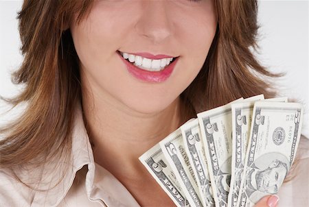 Close-up of a businesswoman holding fanned out dollar bills and smiling Stock Photo - Premium Royalty-Free, Code: 625-01263114