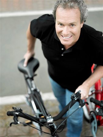 Portrait d'un homme d'âge mûr permanent avec une bicyclette et souriant Photographie de stock - Premium Libres de Droits, Code: 625-01263300