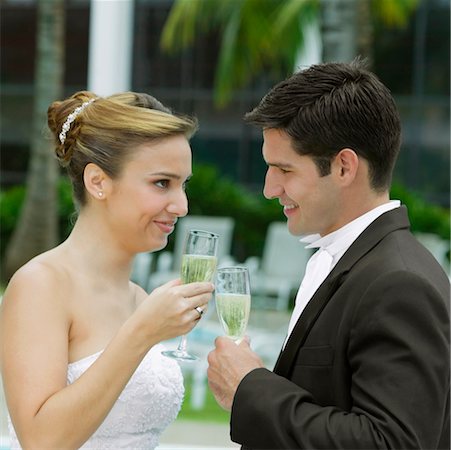 Side profile of a bride and her groom toasting with champagne flutes Stock Photo - Premium Royalty-Free, Code: 625-01263456